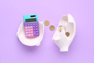 Broken piggy bank with calculator and coins on lilac background