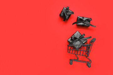 Shopping cart with black gift boxes on red background. Black Friday concept