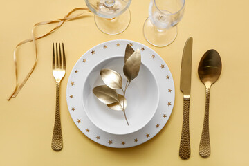 Elegant table setting with golden leaves and cutlery on yellow table