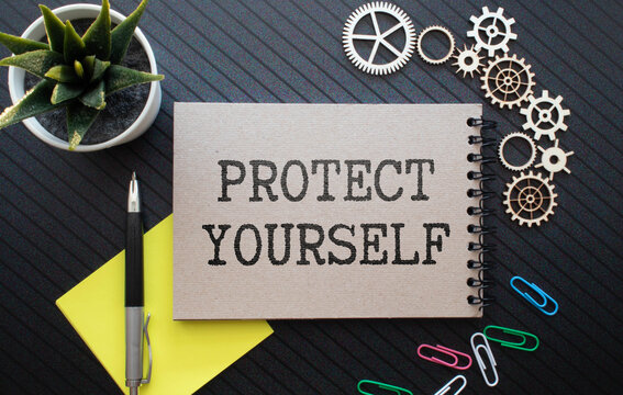 PROTECT YOURSELF word inscription on white card paper sheet in hands of a man. Black letters on white paper.