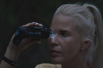 The girl looks through a night vision device in the dark, close-up photo.