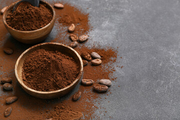 Bowls with cocoa powder and beans on black background