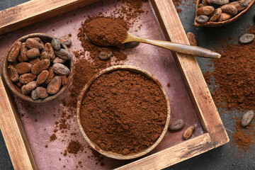 Bowls with cocoa powder and beans on table