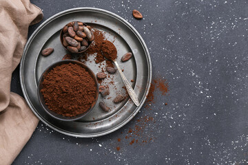 Bowls with cocoa powder and beans on black background