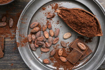 Cocoa pod with powder, beans and chocolate on wooden background