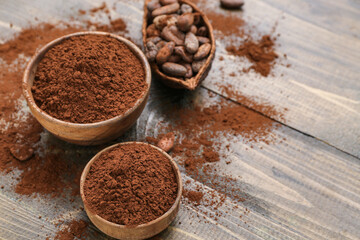 Bowls with cocoa powder on wooden background