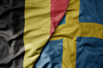 big waving national colorful flag of belgium and national flag of sweden .