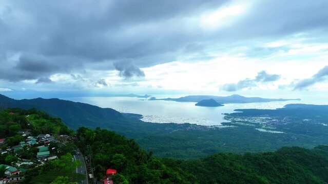 Aerial Forward Shot Of Vehicles On Road By Houses On Mountain Near Taal Lake Against Cloudy Sky - Tagaytay, Philippines