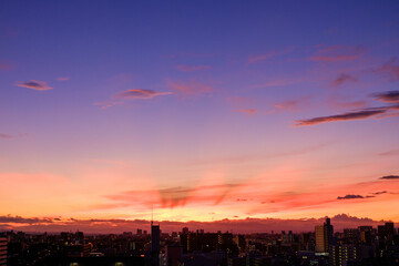 都市の夜明け。東の空が明るくなり雲がまだ昇る前の太陽に照らせら美しいグラデーションを見せる。神戸市内から大阪方面を臨む。