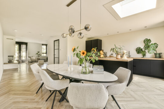 a dining room with wood flooring and black cabinetry in the center of the room is an open kitchen area