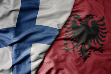 big waving national colorful flag of finland and national flag of albania .