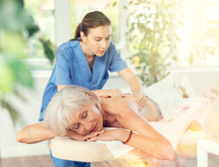 Fototapeta premium Elderly woman client enjoying back massage in spa salon