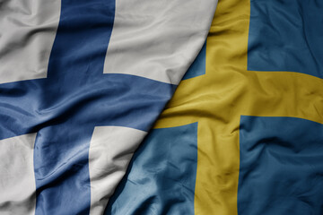 big waving national colorful flag of finland and national flag of sweden .