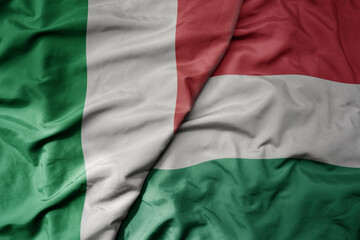 big waving national colorful flag of italy and national flag of hungary .
