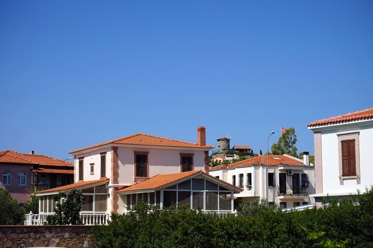 Elegante Villen in Weiß und hellen Pastelltöne mit grünen Gärten im Sommer bei blauem Himmel und Sonnenschein in Cunda bei Ayvalik am Ägäischen Meer in der Provinz Balikesir in der Türkei