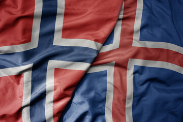 big waving national colorful flag of norway and national flag of iceland .