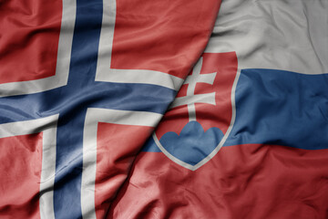 big waving national colorful flag of norway and national flag of slovakia .