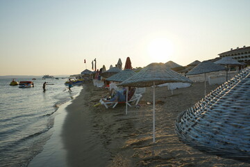 Große runde Sonnenschirme aus Korbgeflecht vor blauem Himmel im Licht der Abendsonne im Sommer am...