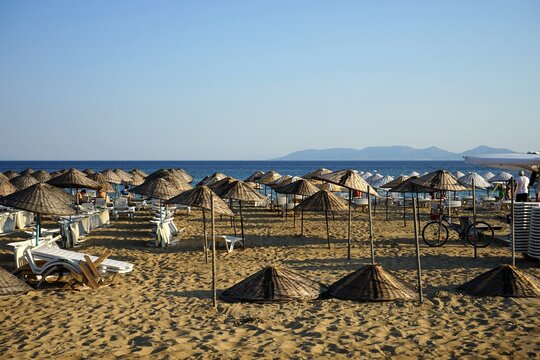 Gro&szlig;e runde Sonnenschirme aus Korbgeflecht vor blauem Himmel im Licht der Abendsonne im Sommer am Strand von Sarimsakli bei Ayvalik in der Provinz Balikesir in der T&uuml;rkei