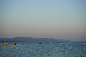 Motorboote vor Anker auf dem Wasser vor blauem Himmel im Licht der Abendsonne im Sommer am Strand...