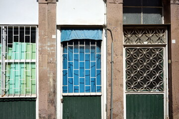 Vergitterte Fenster und Türen mit Sichtschutz in Blau und Grün eines heruntergekommenen Altbau im...