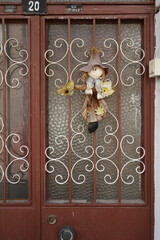 Alte Tür mit Verzierung aus Schmiedeeisen, Riffelglas und Puppe als Glücksbringer eines Altbau im...