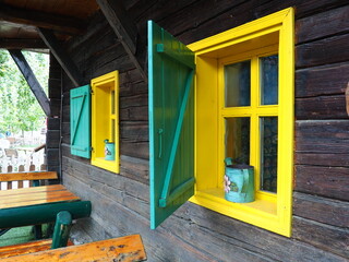 Ethno-folk wooden shutters on a window with a wooden frame, painted green and yellow. Vintage...