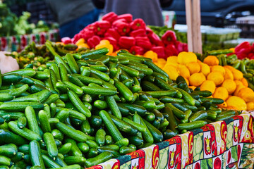 Tables full of fruits and vegetables at market with people wandering isle in background