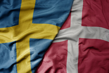 big waving national colorful flag of sweden and national flag of denmark .