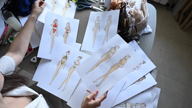 Woman looking at sketches of underwear. 