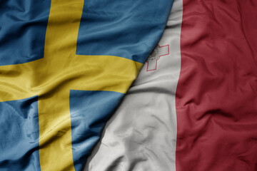 big waving national colorful flag of sweden and national flag of malta .
