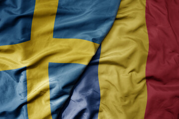 big waving national colorful flag of sweden and national flag of romania .