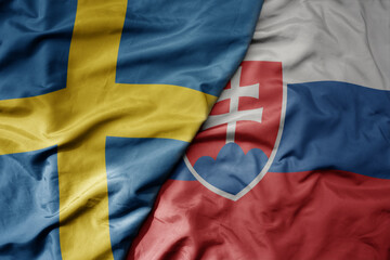 big waving national colorful flag of sweden and national flag of slovakia .