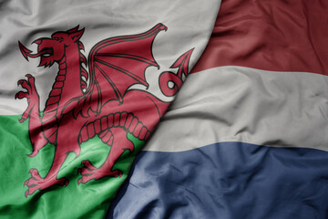 big waving national colorful flag of wales and national flag of netherlands .