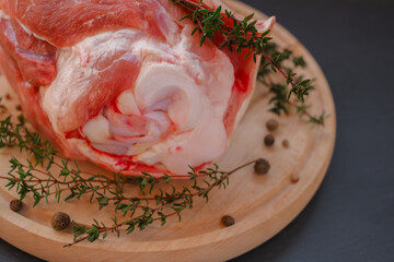 Pork knuckle.Pork meat on the bone, peppercorns, fresh thyme on a black slate background. Fresh meat products  - obrazy, fototapety, plakaty