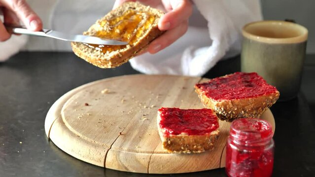 Buns with honey and jam. Hands spread honey on a fresh bun. Sweet breakfast. 4k footage