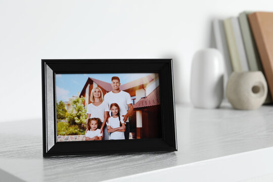 Frame with family photo on white chest of drawers indoors