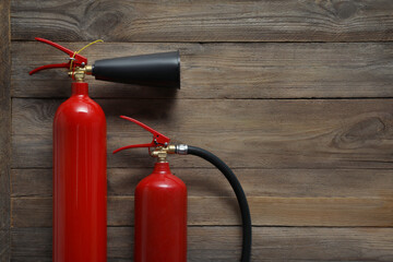 Naklejka premium Two fire extinguishers on wooden background, flat lay. Space for text