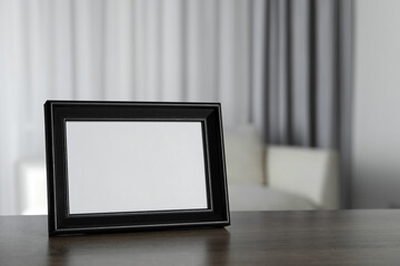 Empty square frame on wooden table indoors, space for text © New Africa