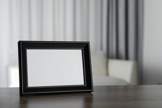 Empty square frame on wooden table indoors, space for text