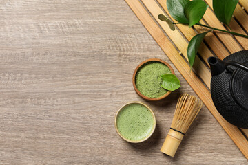Cup of fresh matcha tea, bamboo whisk, teapot and green powder on wooden table, flat lay. Space for text