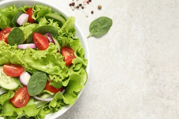 Delicious salad in bowl on light grey table, top view. Space for text