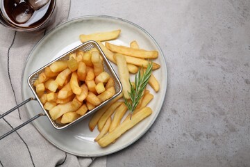 Tasty french fries with rosemary and soda drink on light grey table, flat lay. Space for text