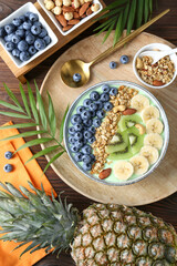 Tasty smoothie bowl with fresh fruits and oatmeal served on wooden table, flat lay