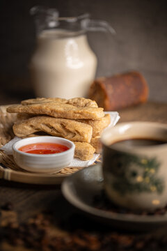 Keropok Lekor or Fried Fish Cake on a Rattan Plate with a Sweet Chilli Sauce and on Wooden Table. Malaysian Snacks. Asian Foods.