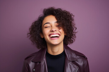 Fototapeta na wymiar Portrait of beautiful young woman with curly hair smiling on purple background