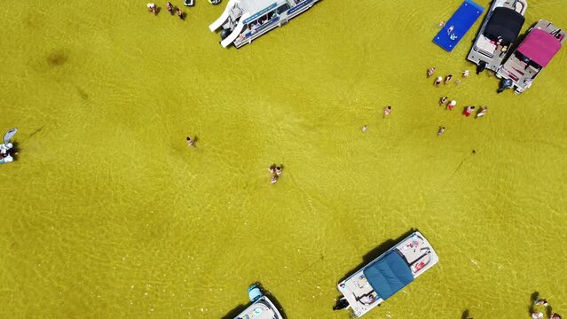 Diverse kids and adults enjoy wading, swimming, pontoon, boat rentals, jet skis, paddleboards, relax at low tide shallow brackish water of Crab Island, Destin, Florida