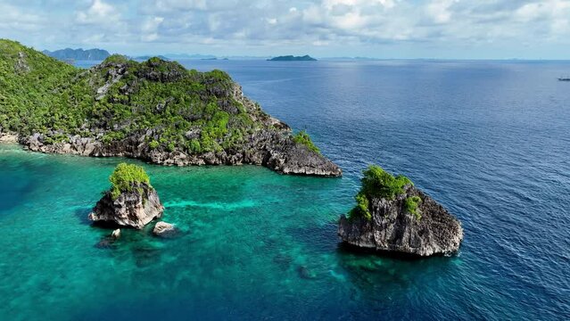 Aerial Panning Shot Of Green Plants Over Island Near Boats On Blue Sea Against Sky - Raja Ampat, Indonesia