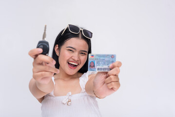 A proud and elated young woman showing off her new driver's license and keys to the new car. Isolated on a white background.
