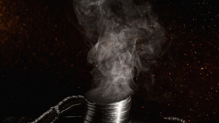 Burn smoke. Fire sparks floating. Global warming. White chemical fume ash flying over flexible exhaust duct pipe on dark black abstract empty space background.